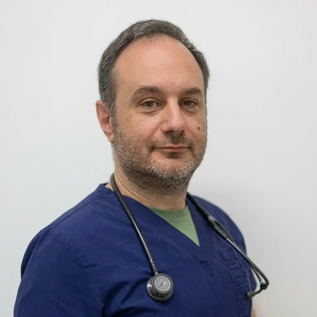 Dr Cemali Aksogut, GMC-registered Private General Practitioner and UK CAA Approved Aeromedical Examiner, wearing blue scrubs and a stethoscope.