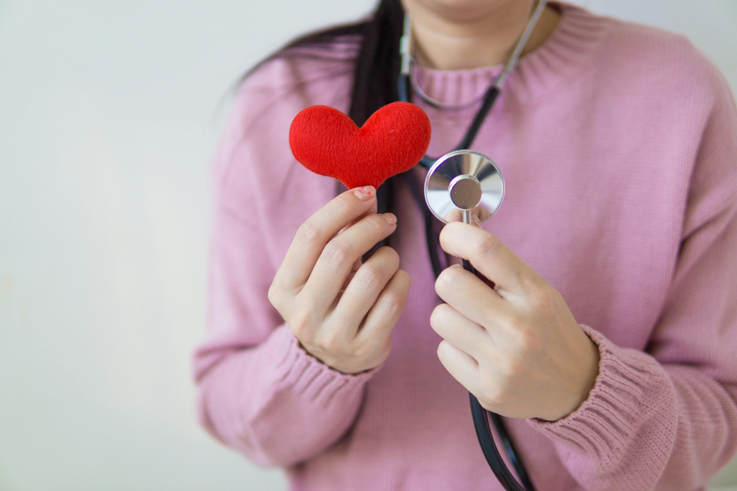 A person holding a red plush heart and a stethoscope, symbolizing expert treatments and procedures in cardiology available at LSDC Healthcare London.